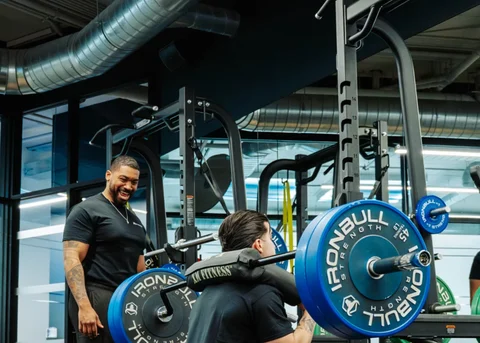 A coach beside a member performing a barbell squat at Dynamix