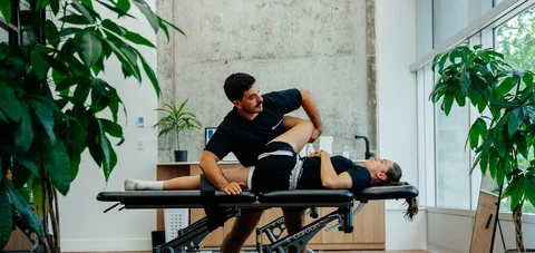 A person receiving an assisted leg stretch on a treatment table at Dynamix